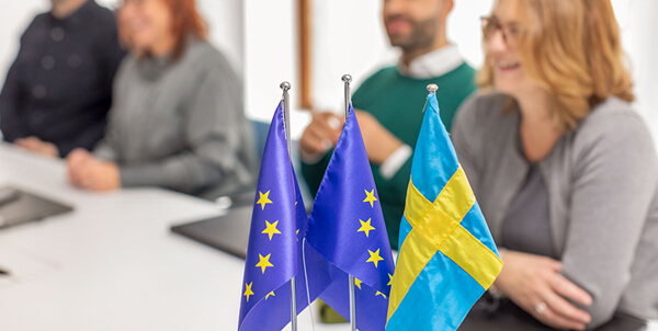 Flaggor framför sittande medarbetare. Foto: Susanne Kronholm