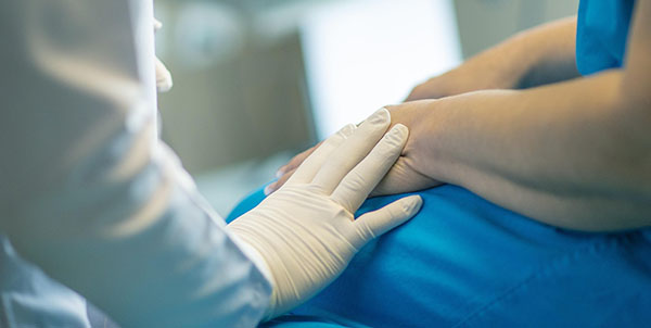 Vårdpersonals hand på patients arm.