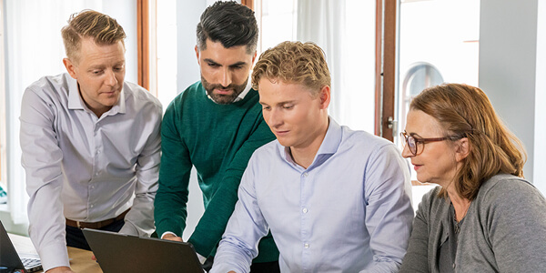 Medarbetare står runt en datorskärm.