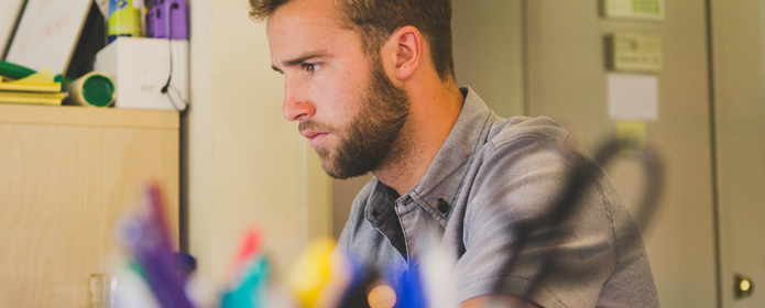 Man som ser koncentrerad ut med pennor i förgrunden.